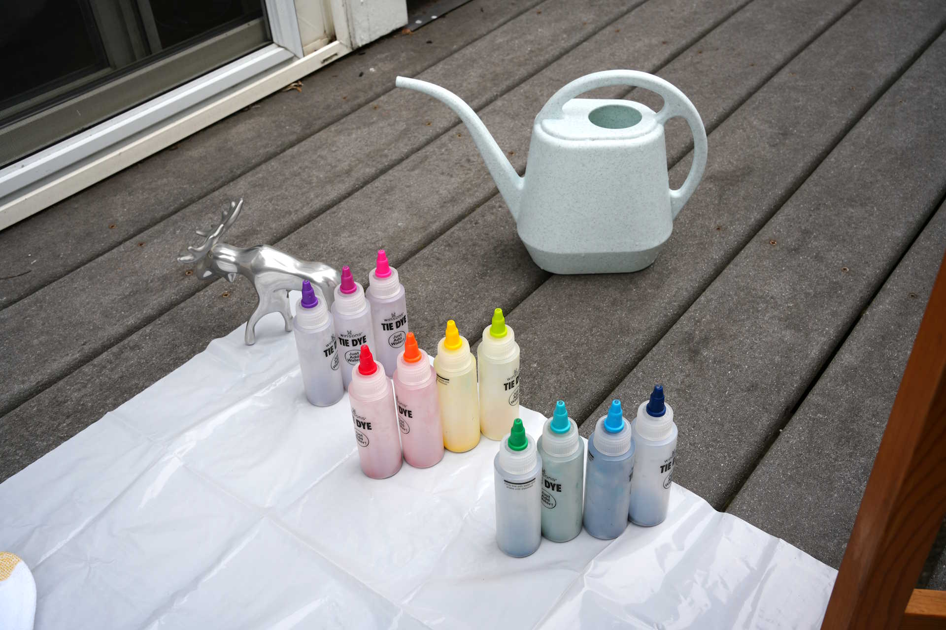 bottles of dye on a balcony beside white socks on a plastic sheet