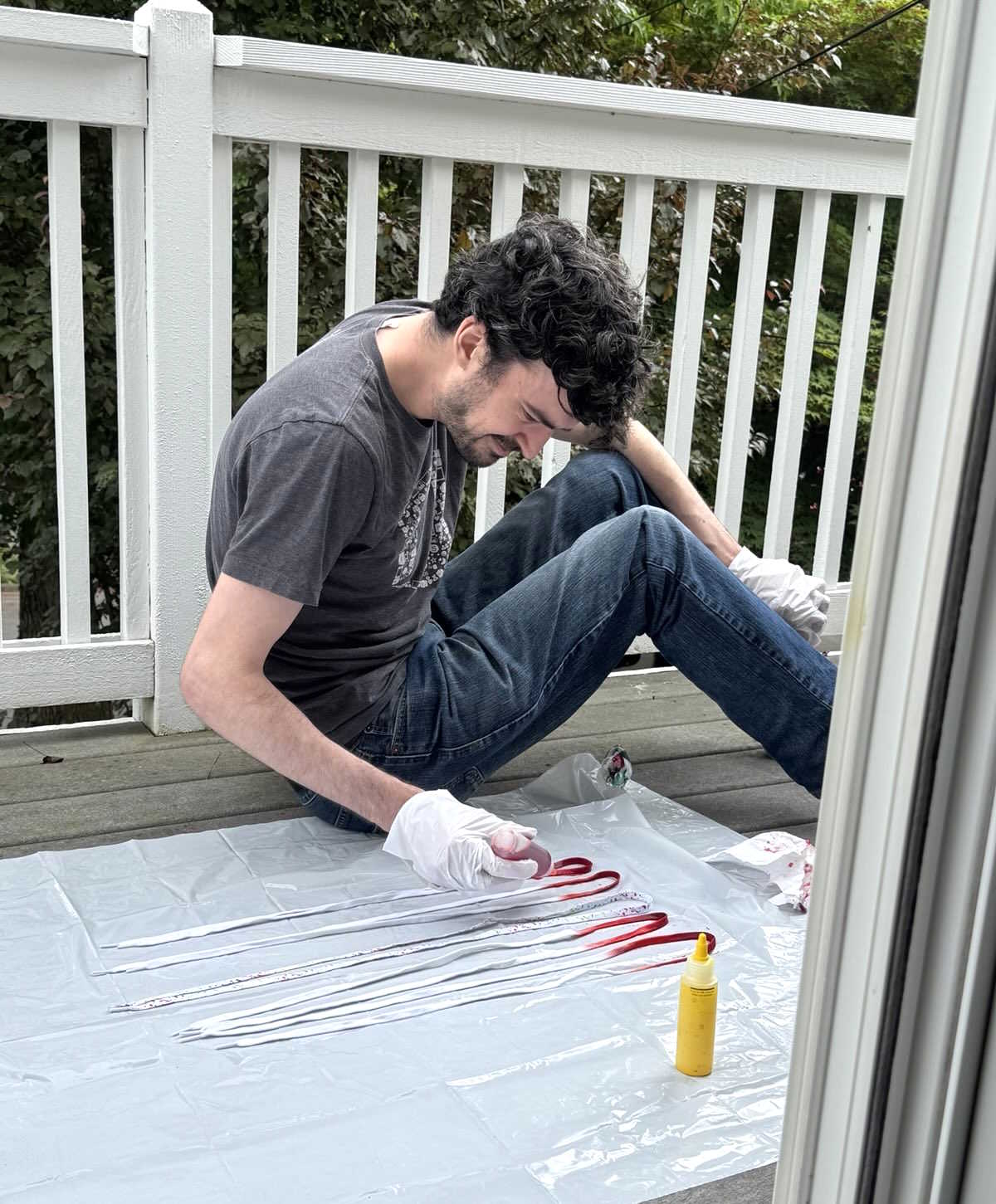 man applying red dye to white laces with a dropper