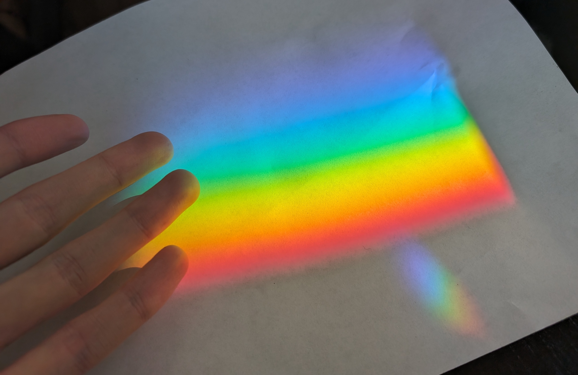 showing a piece of paper with a rainbow projected onto it in a dark room